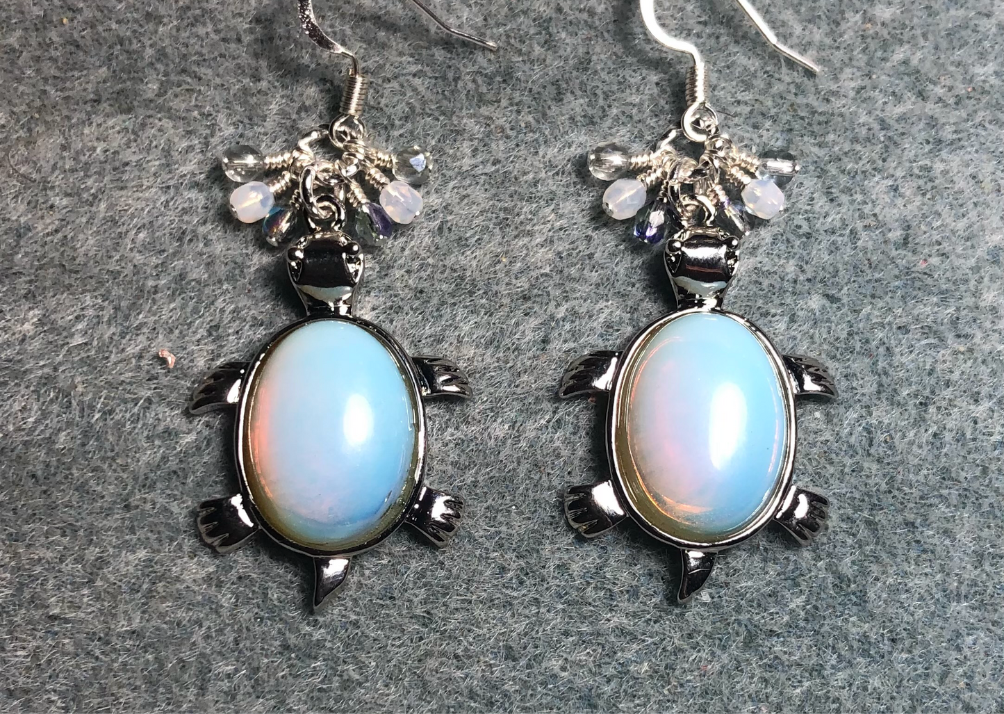 Large silver and opalite gemstone turtle charm earrings adorned with small dangling white, clear, and light blue Czech glass beads.