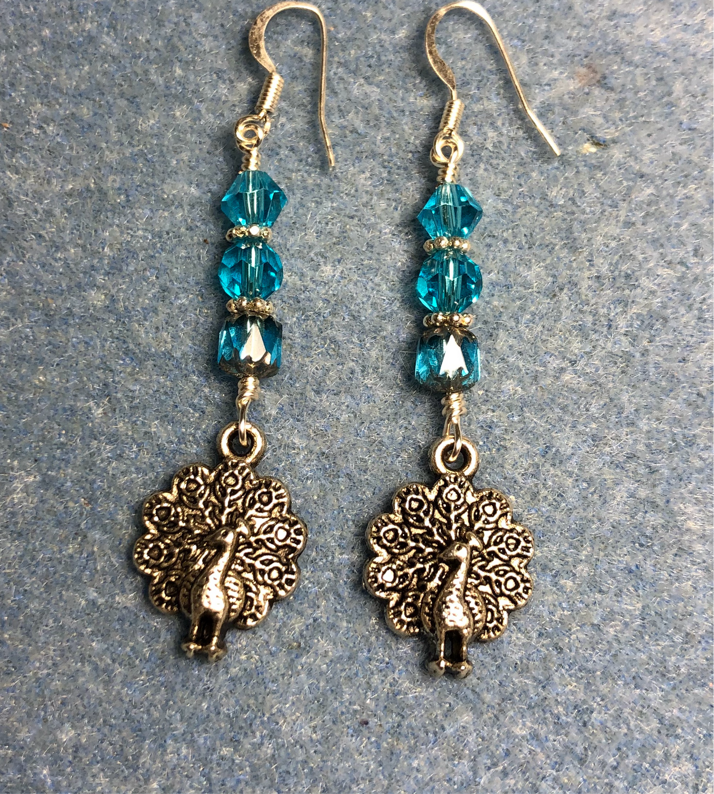 Silver peacock charm earrings adorned with turquoise Czech glass beads