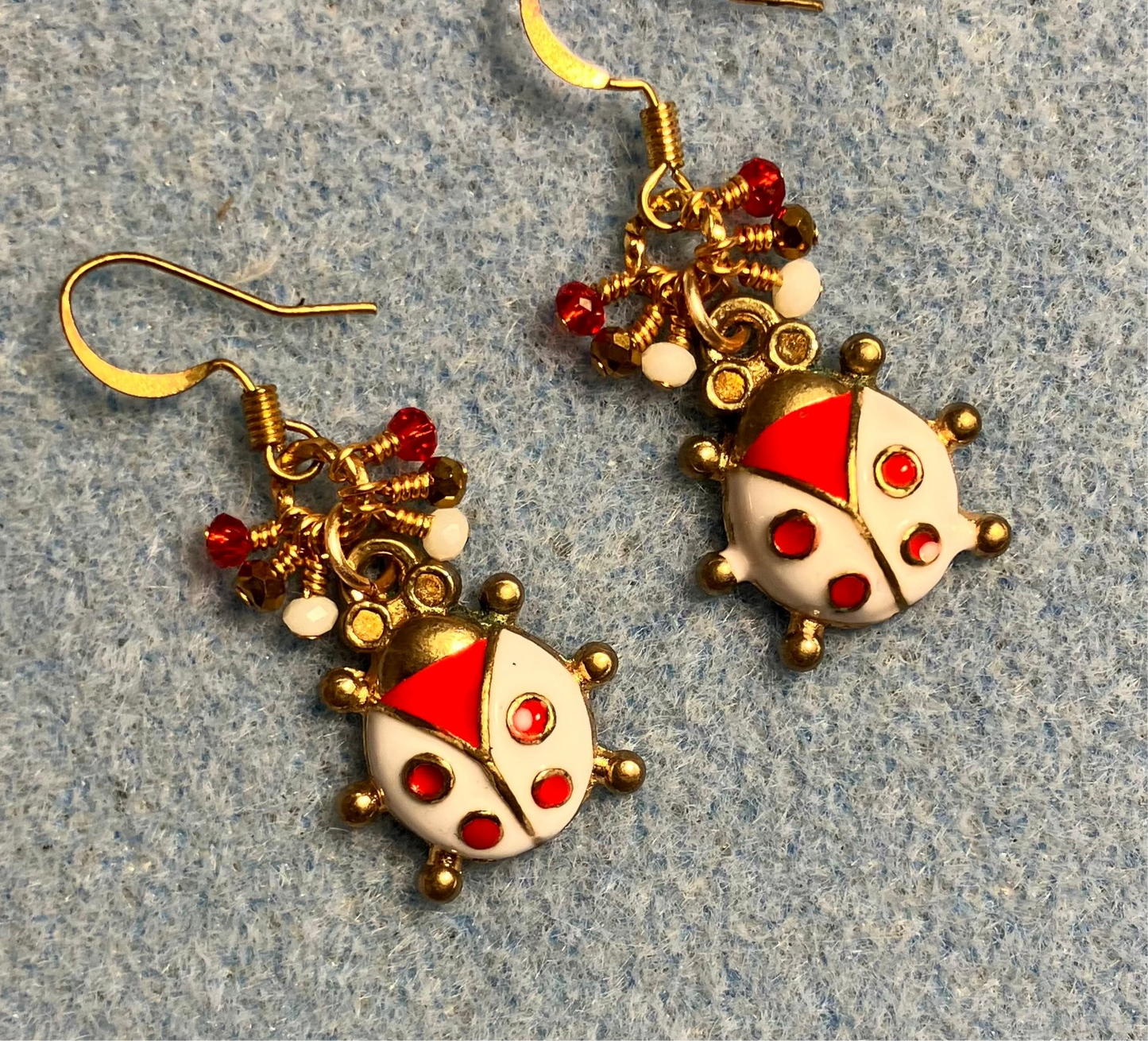 Red, white, and gold enamel ladybug charm earrings adorned with tiny dangling red, white, and gold Chinese crystal beads.