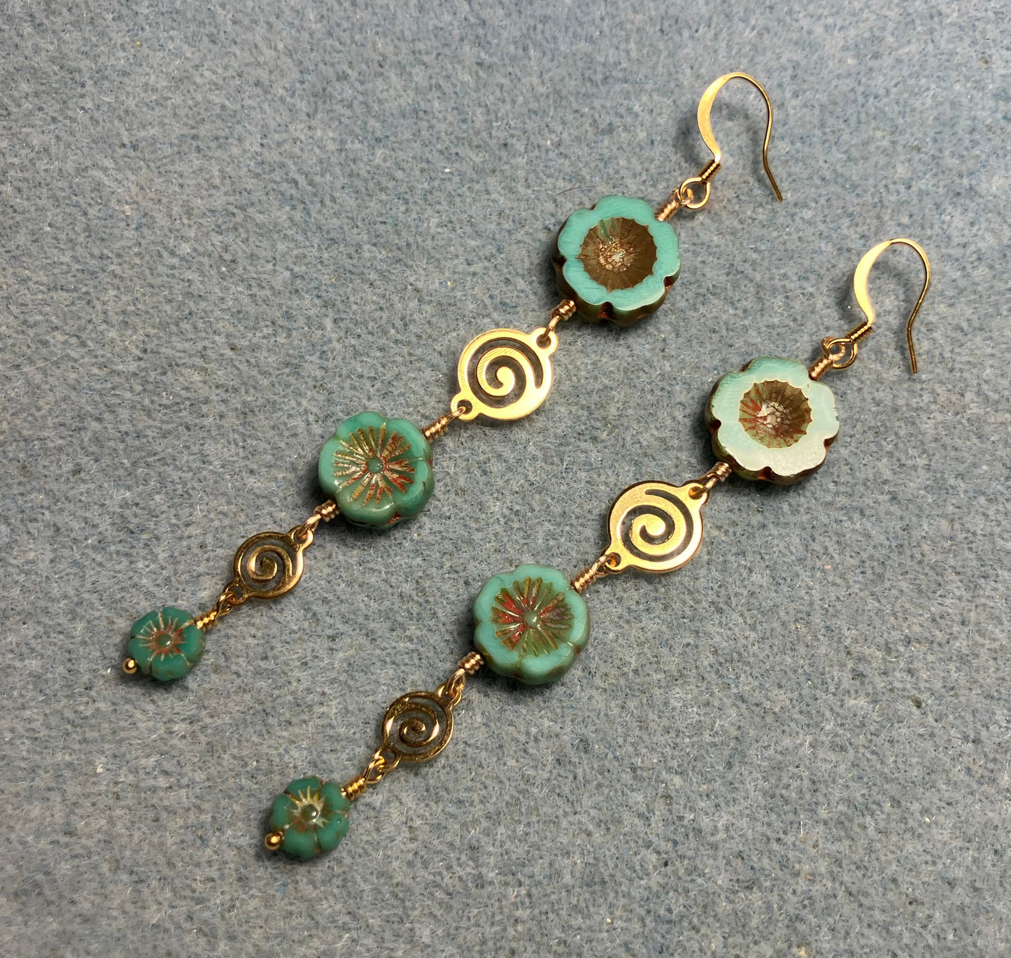 Extra long green and brown flower bead earrings made with three sizes of green and brown Czech glass pansy beads joined by gold swirly connectors.