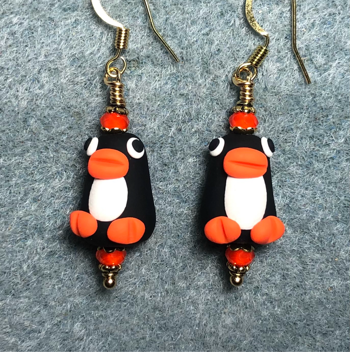 Black, white, and orange polymer clay penguin bead earrings adorned with orange Chinese crystal beads.