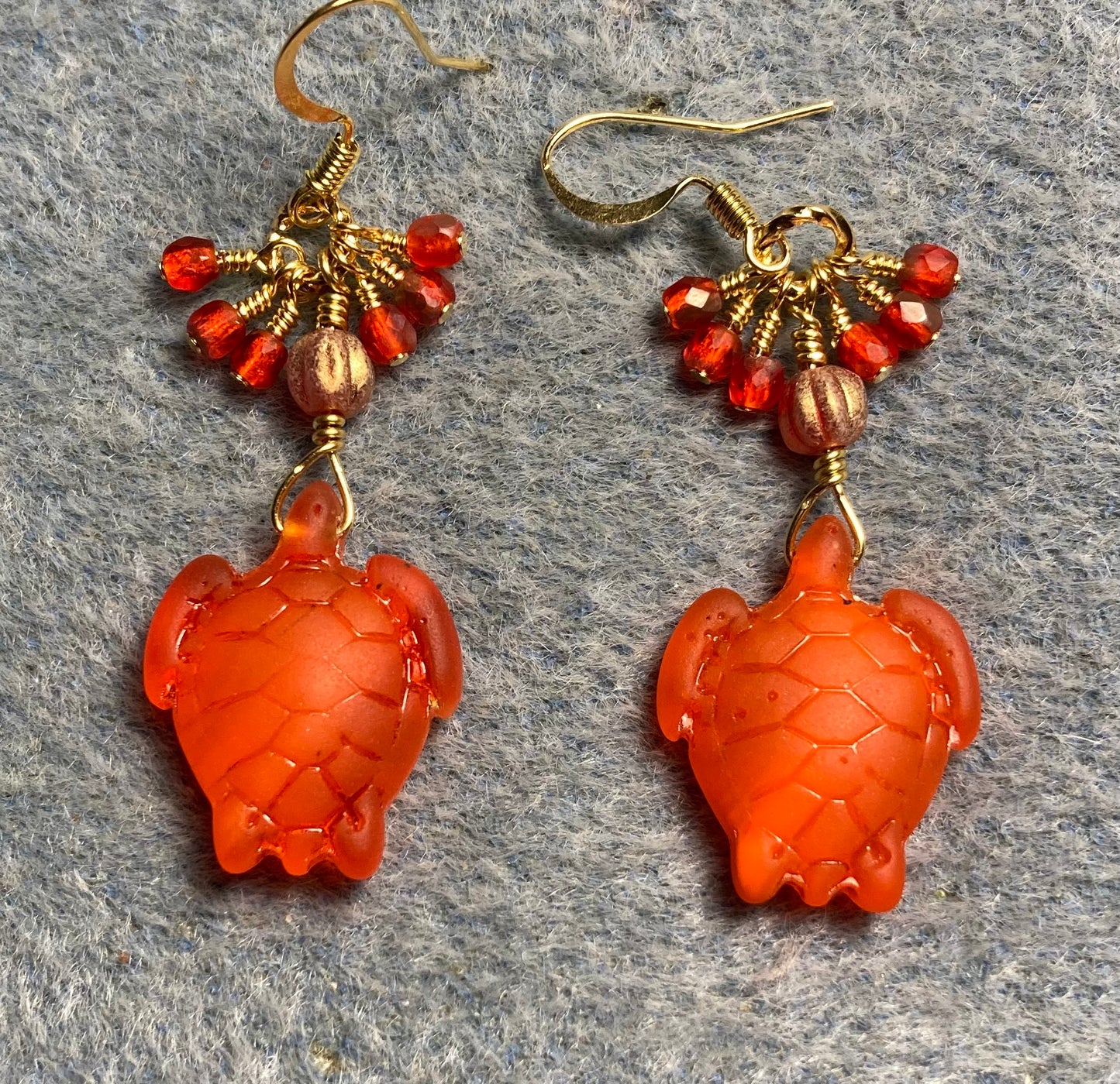 Opaque orange sea glass sea turtle bead earrings adorned with orange Czech glass beads and small dangling orange Czech glass beads.