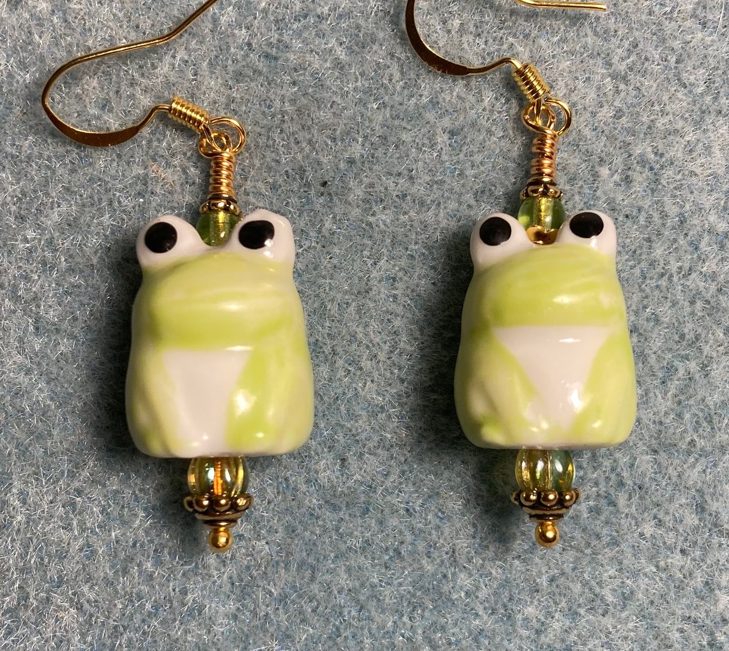 Olive green and white ceramic frog bead earrings adorned with olive green Czech glass beads.