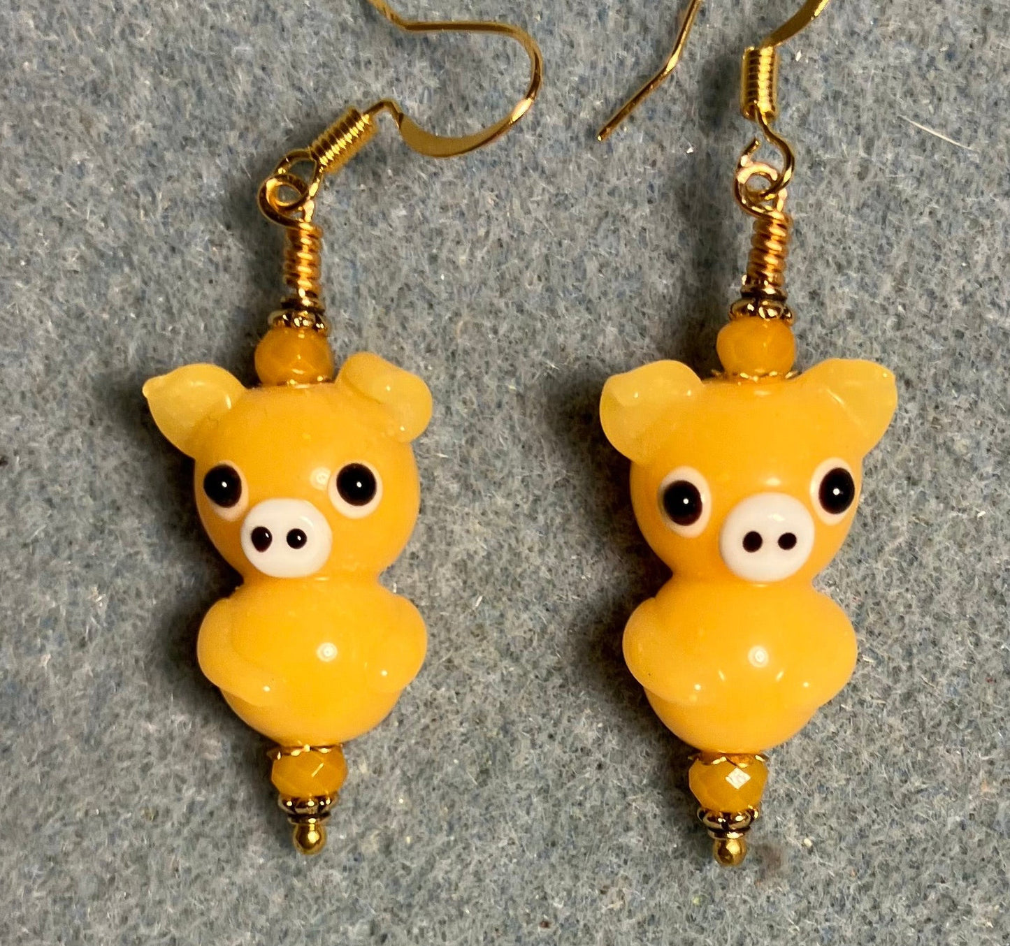 Amber yellow lamp work standing pig bead earrings adorned with amber yellow Chinese crystal beads.
