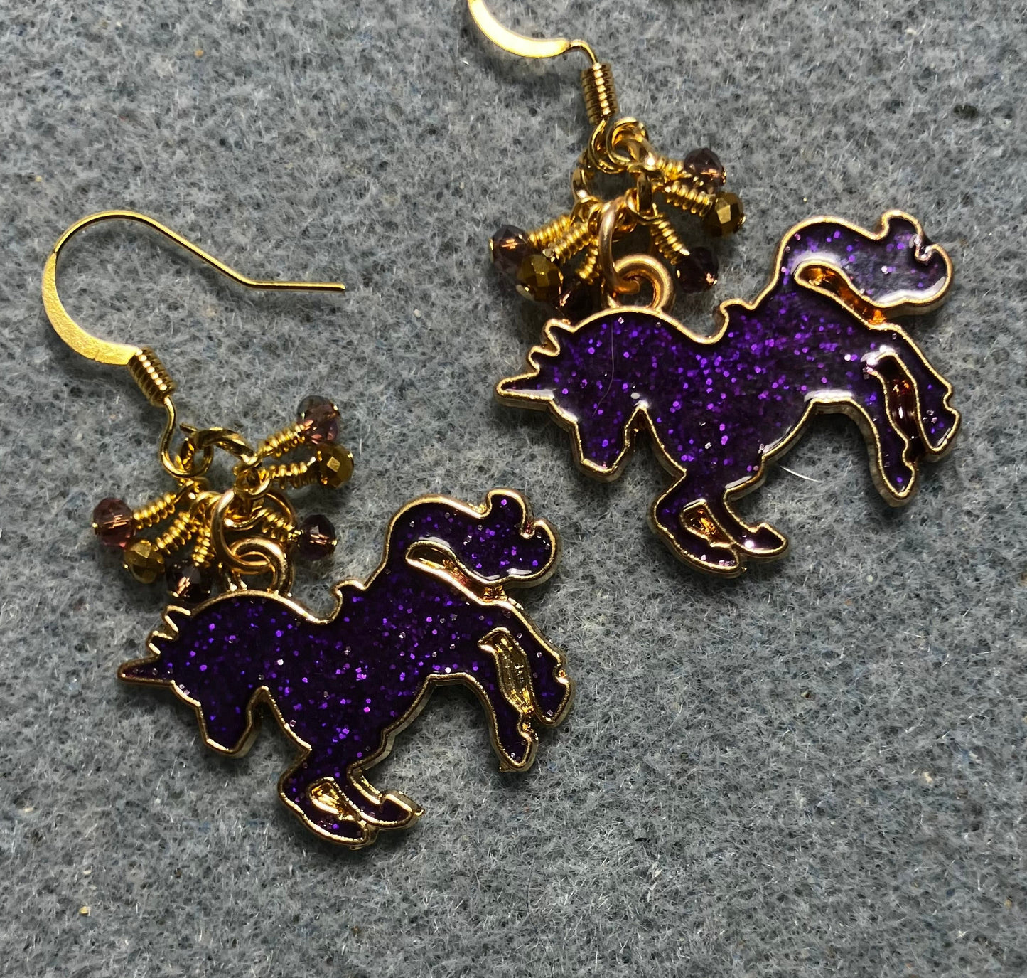 Purple and gold enamel sparkly unicorn charm earrings adorned with tiny dangling purple and gold Chinese crystal beads.