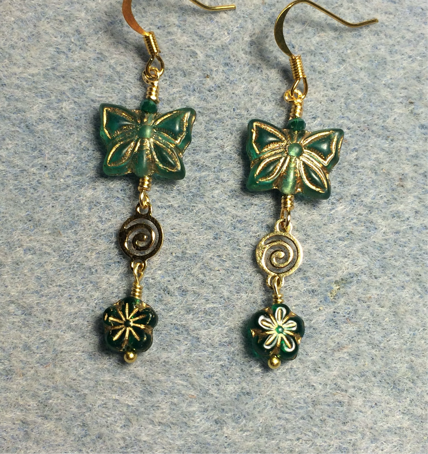 Emerald green Czech glass butterfly bead earrings adorned with gold swirly connectors and emerald green Czech glass daisy beads.