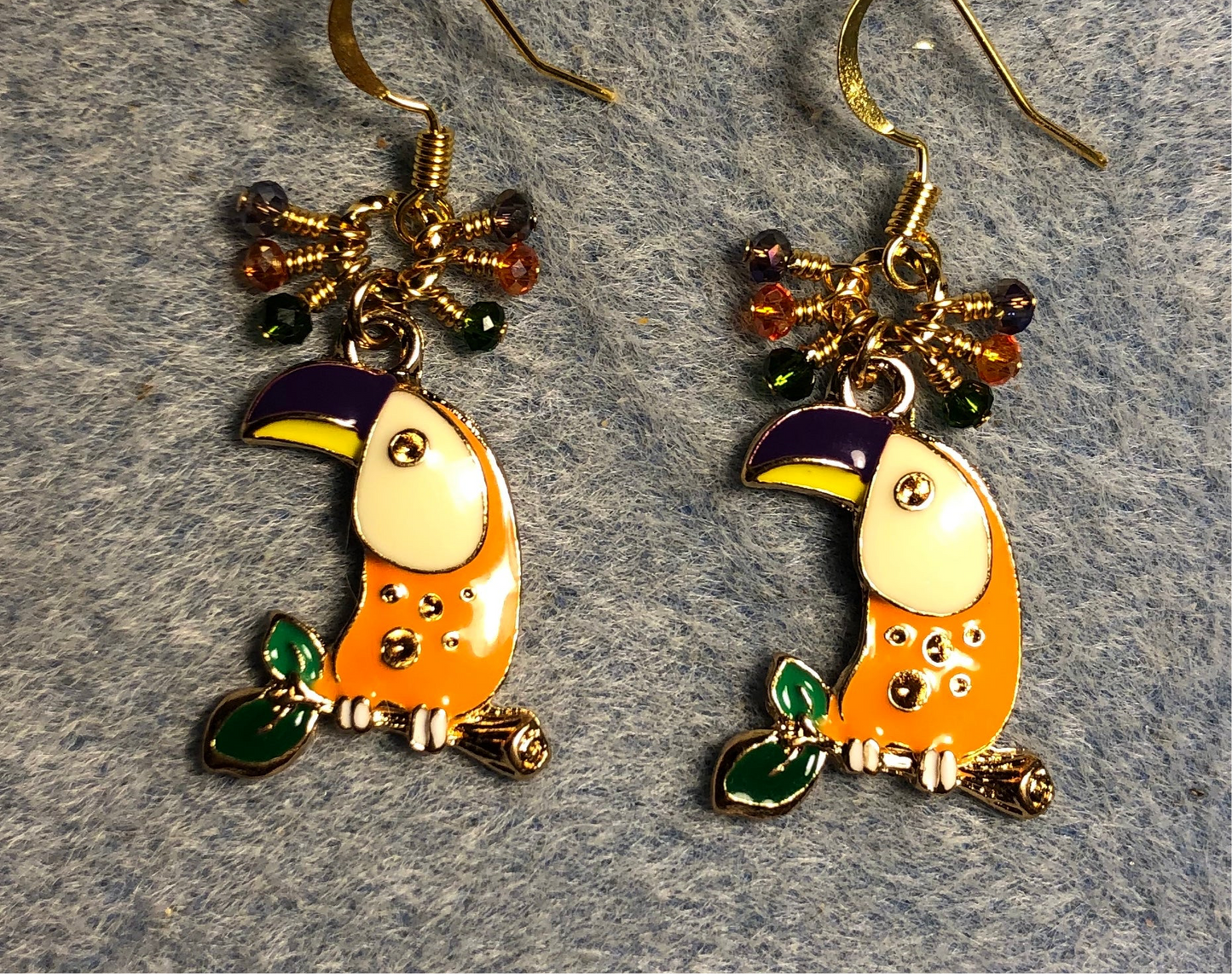 Orange, purple, and green enamel toucan charm earrings adorned with tiny dangling orange, purple, and green Chinese crystal beads.