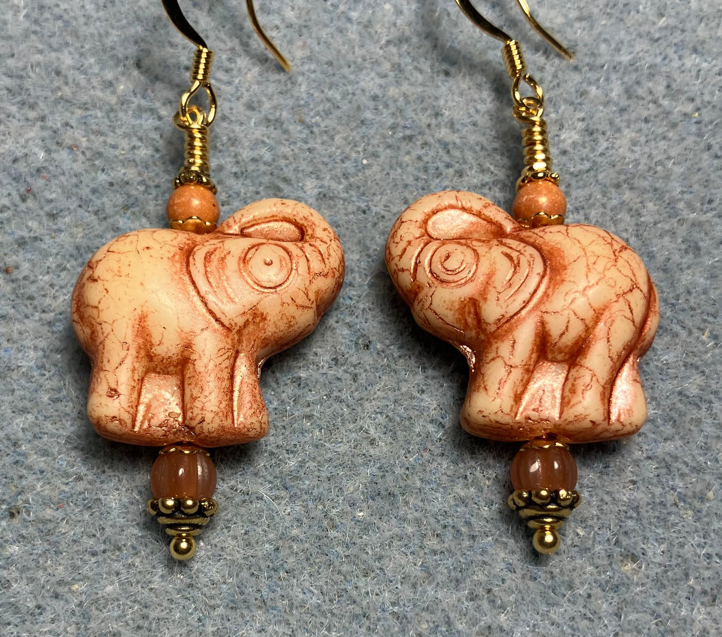 Light beige (with orange inlay) Czech glass elephant bead earrings adorned with orange Czech glass beads.