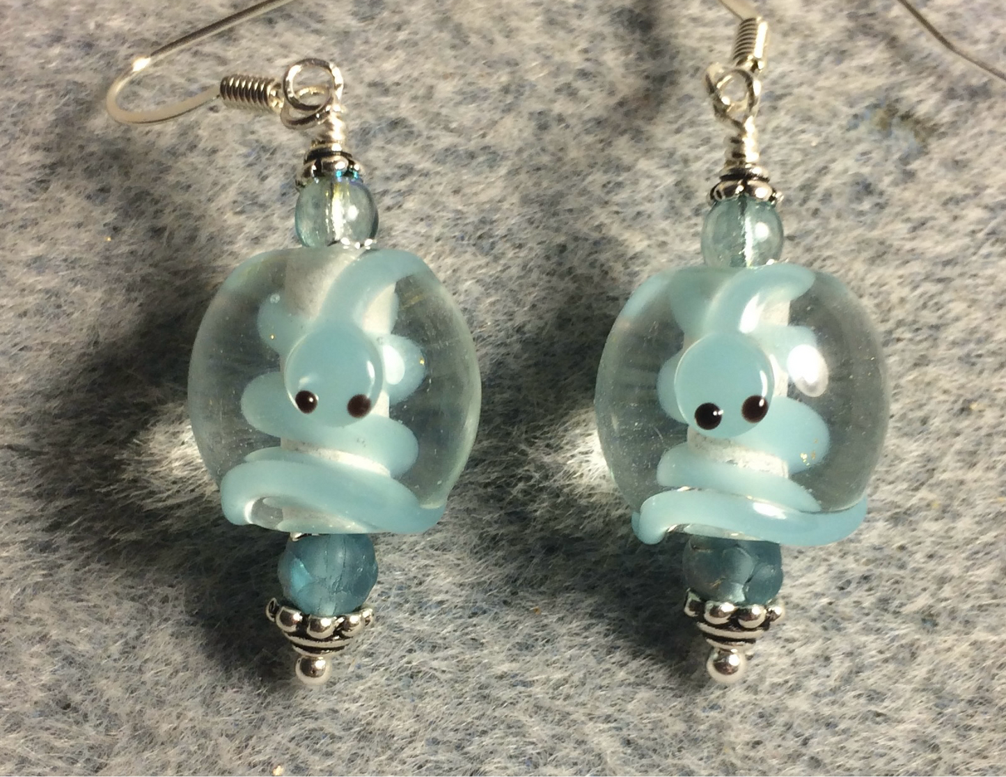 Clear and light turquoise lamp work snake bead earrings adorned with light turquoise Czech glass beads.