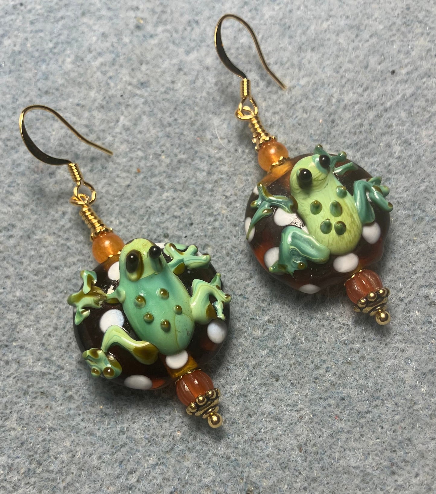 Orange and green lamp work frog bead earrings adorned with orange Czech glass beads.