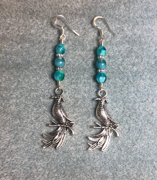 Long silver phoenix charm earrings adorned with milky turquoise Czech glass beads