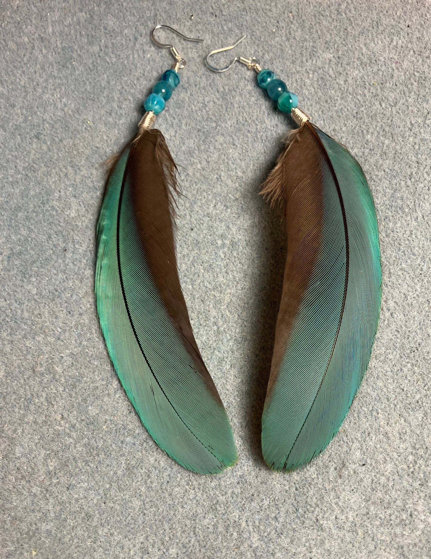 Turquoise blue macaw feather earrings adorned with turquoise Czech glass beads.