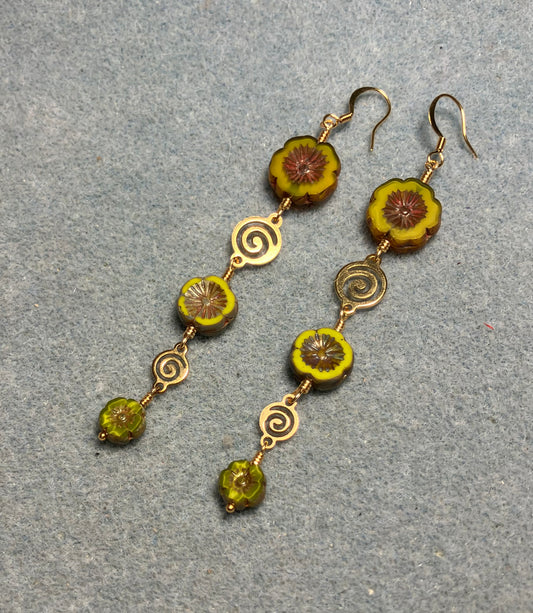 Extra long mustard green flower bead earrings made with three sizes of mustard green Czech glass pansy beads joined by gold swirly connectors.