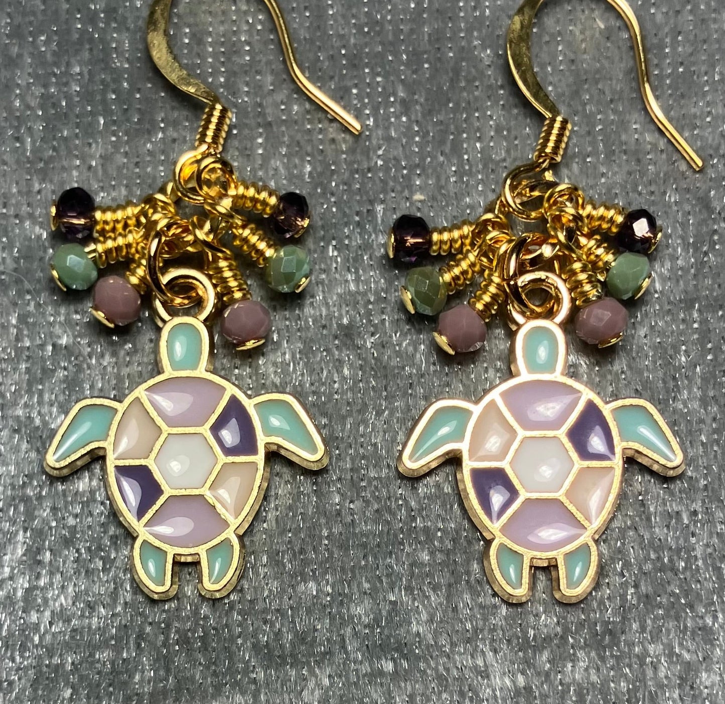 Purple, light green, and violet enamel sea turtle charm earrings adorned with tiny dangling purple, light green, and violet Chinese crystal beads.