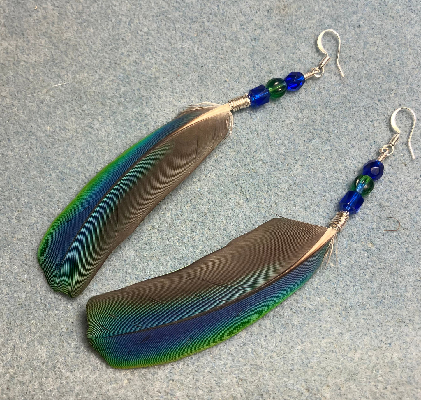 Very rare iridescent blue and green Pionus feather earrings adorned with blue and green Czech glass beads.