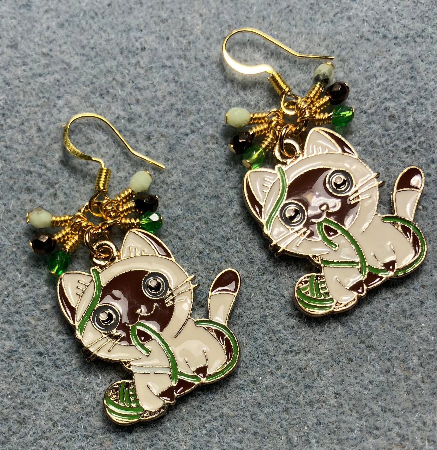 Brown, white, and green enamel cat charm earrings adorned with small dangling brown, white, and green Czech glass beads.