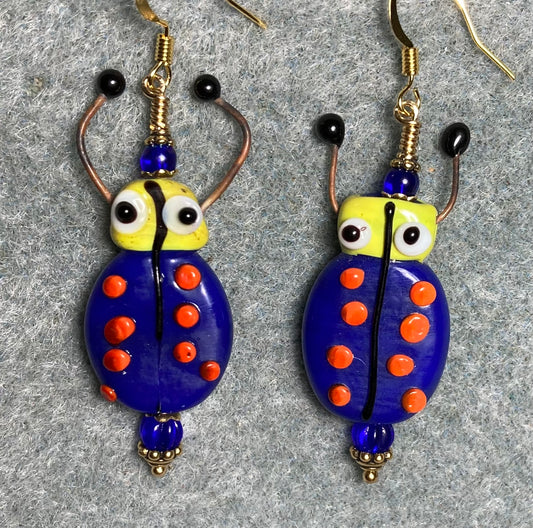 Dark blue, red, and yellow lamp work beetle bead earrings adorned with dark blue Czech glass beads.