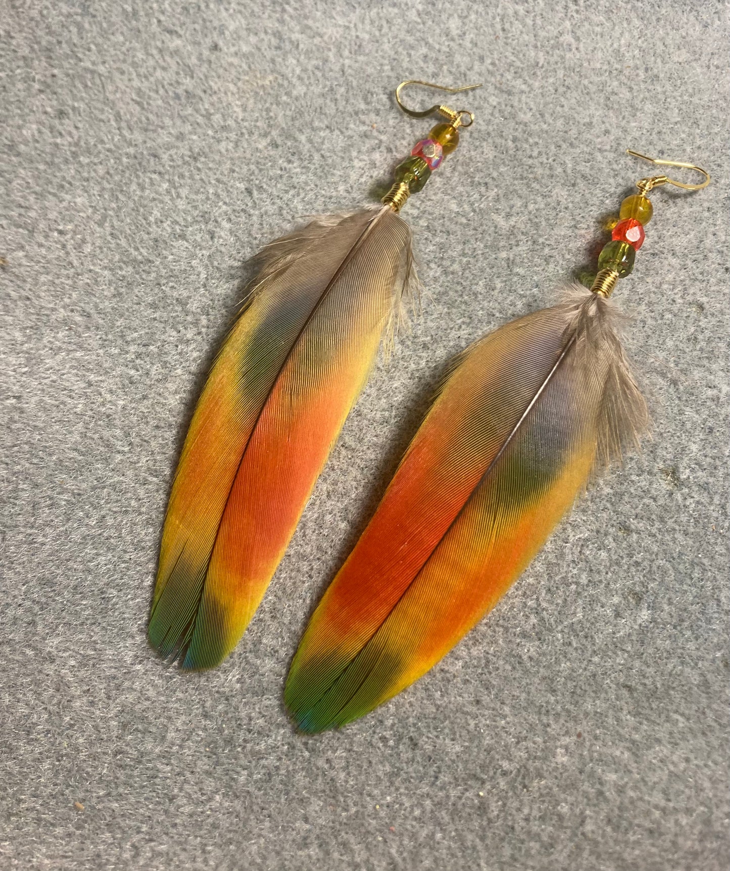 Red, green, and yellow scarlet macaw feather earrings adorned with red, green, and yellow Czech glass beads.