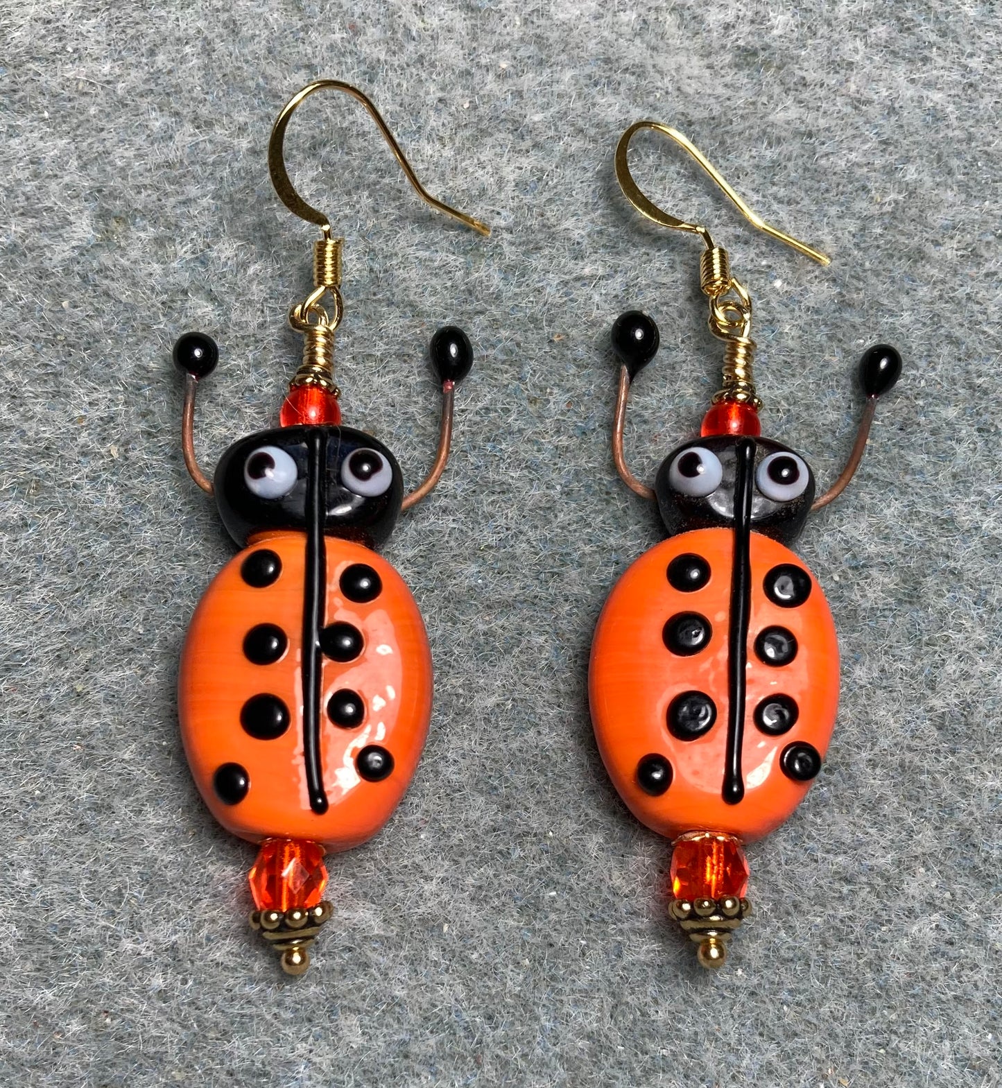 Orange and black lamp work beetle bead earrings adorned with orange Czech glass beads.