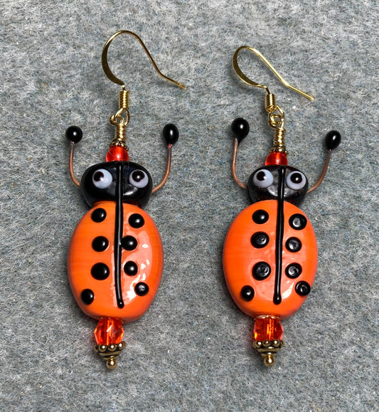 Orange and black lamp work beetle bead earrings adorned with orange Czech glass beads.