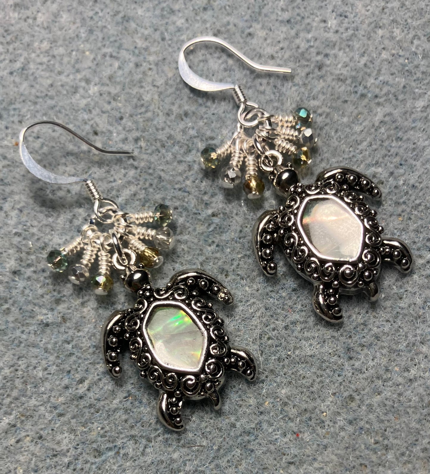 Ornate silver and abalone turtle charm earrings adorned with tiny dangling green and silver Chinese crystal beads.