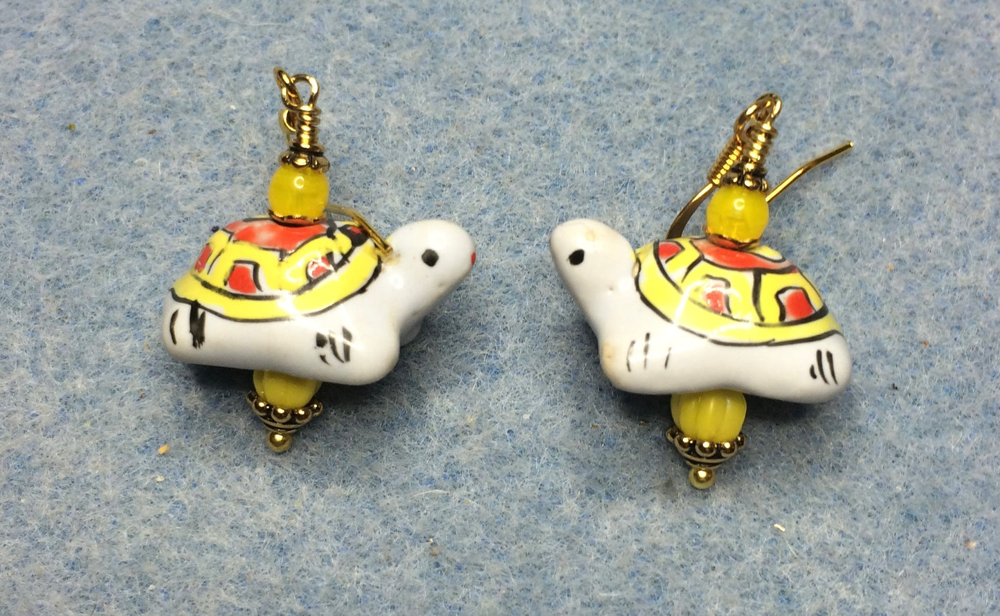 Yellow, orange, and white ceramic turtle bead earrings adorned with yellow Czech glass beads.