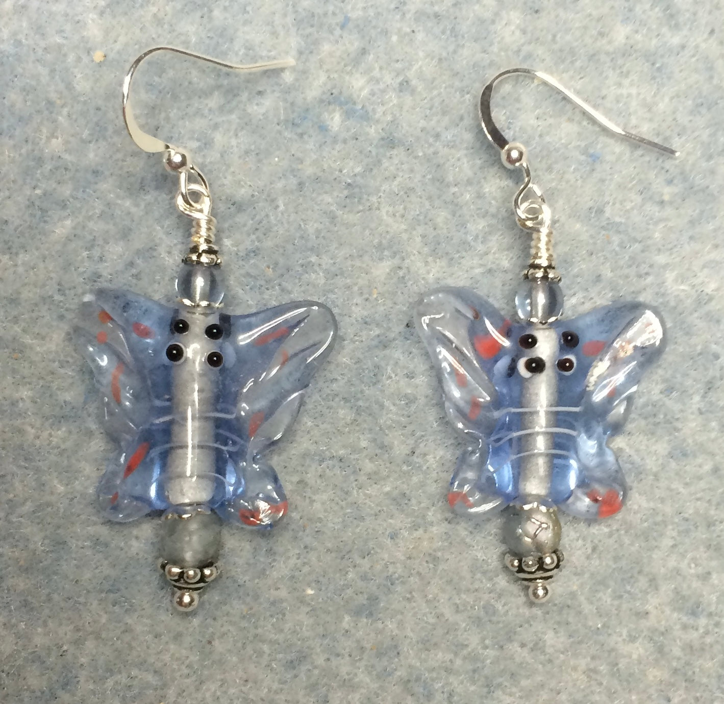 Light blue lamp work butterfly bead earrings adorned with light blue Czech glass beads.