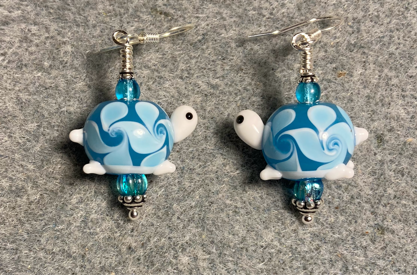 Light turquoise lamp work turtle bead earrings adorned with light turquoise Czech glass beads.