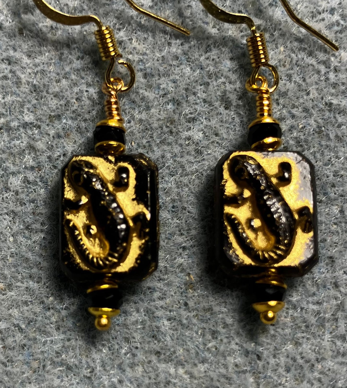 Small black and gold Czech glass lizard bead earrings adorned with black Chinese crystal beads.