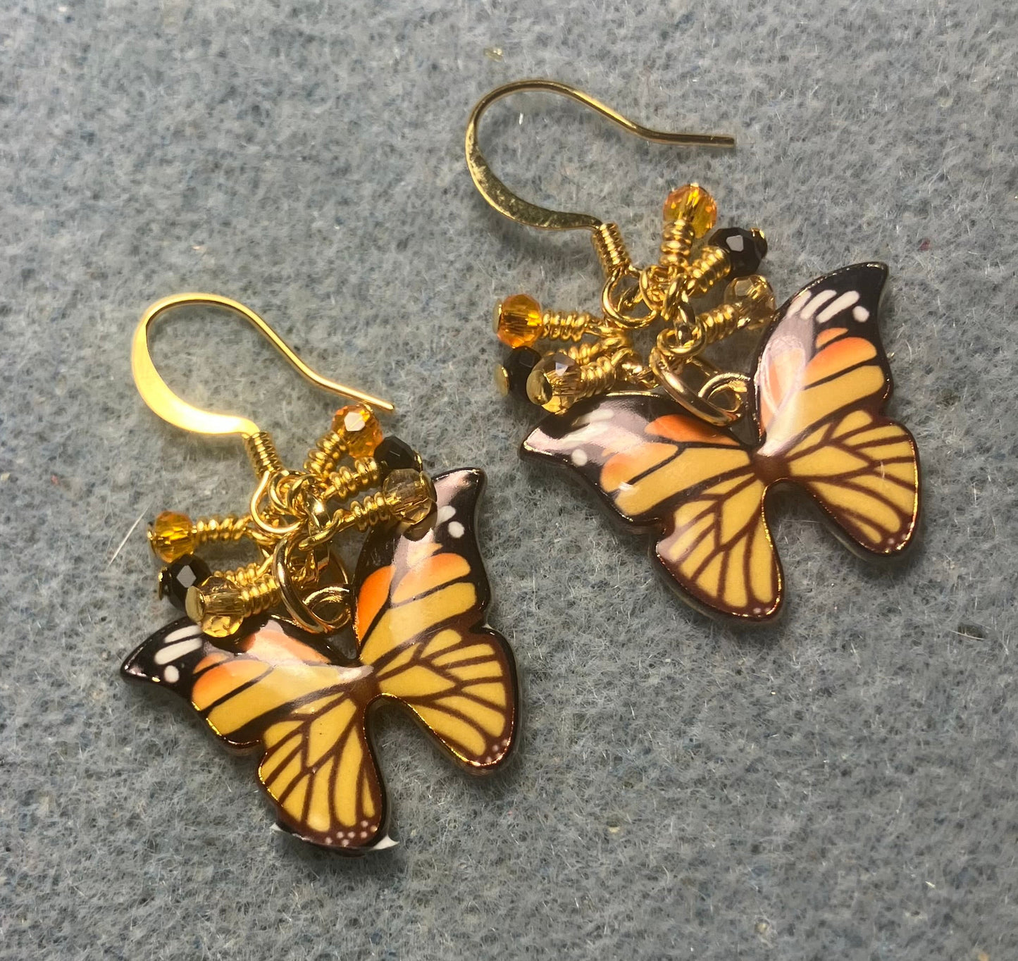 Orange and black enamel butterfly charm earrings adorned with tiny dangling orange, black, and amber Chinese crystal beads.