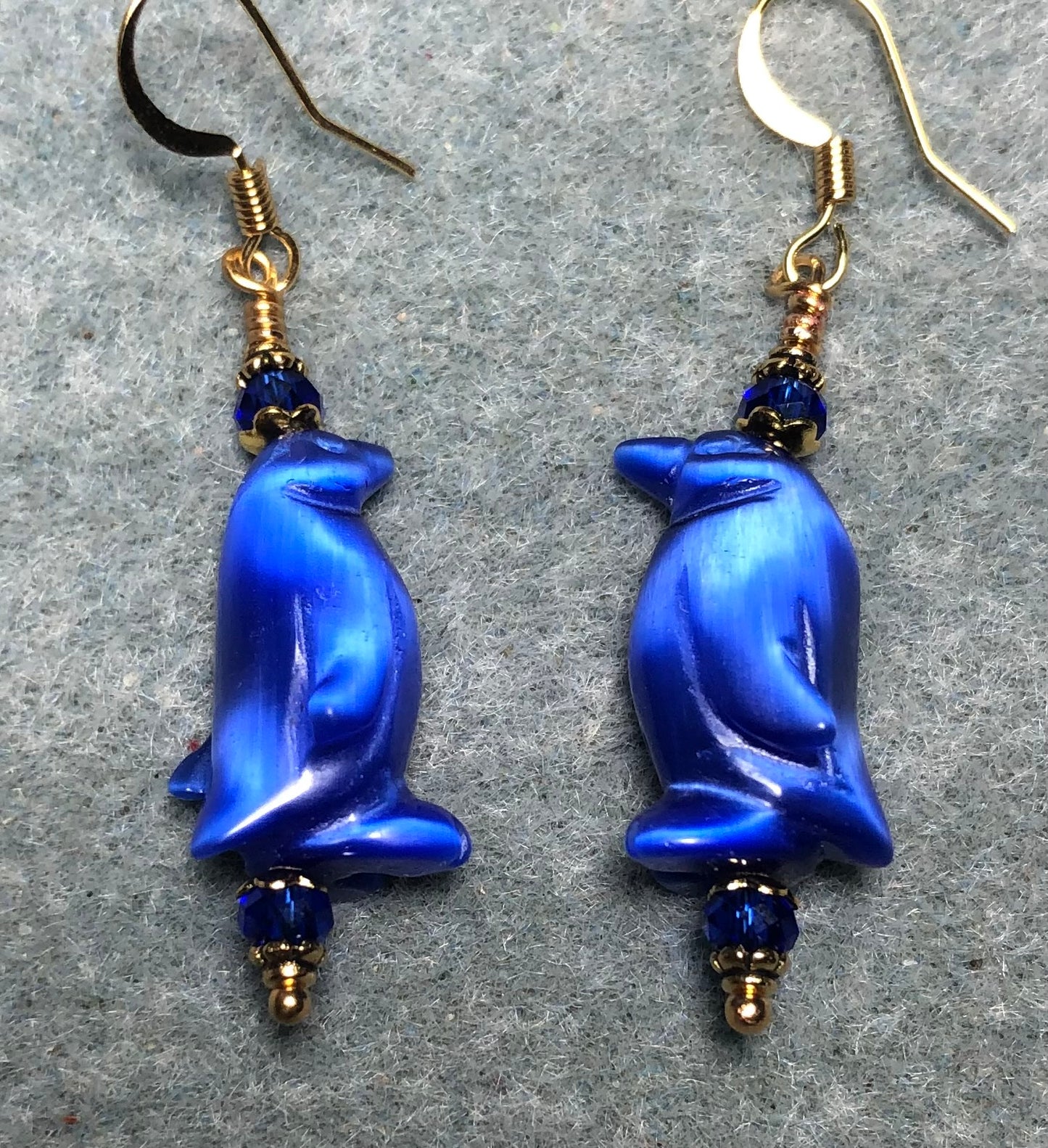 Blue fiber optic (cat’s eye) penguin bead earrings adorned with dark blue Chinese crystal beads.