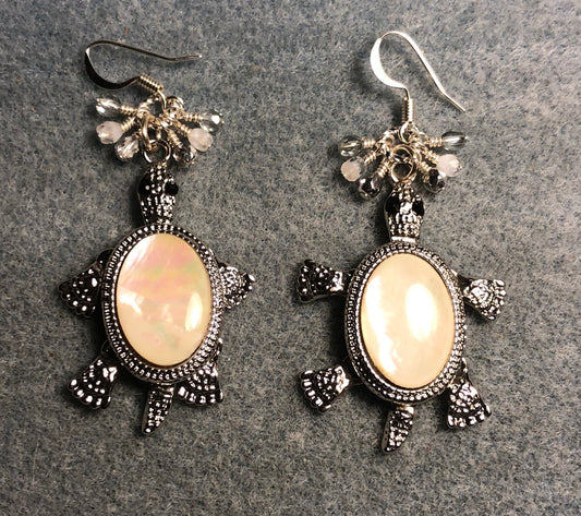 Large silver white mother of pearl turtle charm earrings adorned with small dangling white, silver, and clear Czech glass beads.