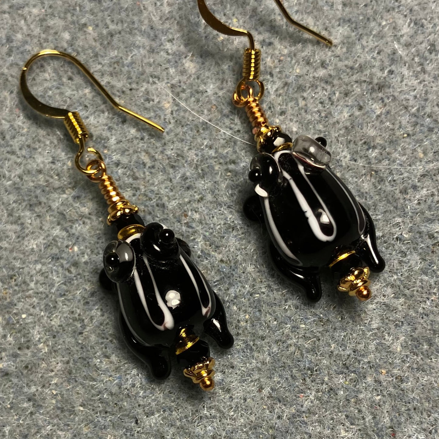Very small black with white stripes lamp work frog bead earrings adorned with black Chinese crystal beads.