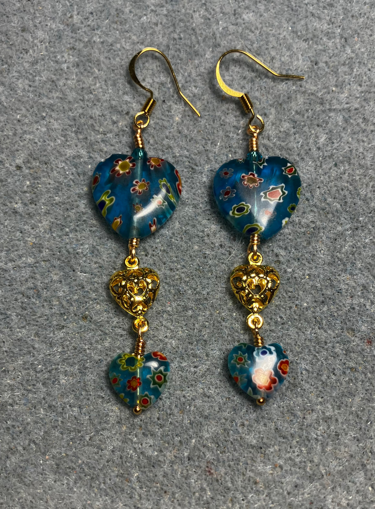 Large and small matching turquoise millefiori glass heart bead earrings joined by gold filigree heart connectors.