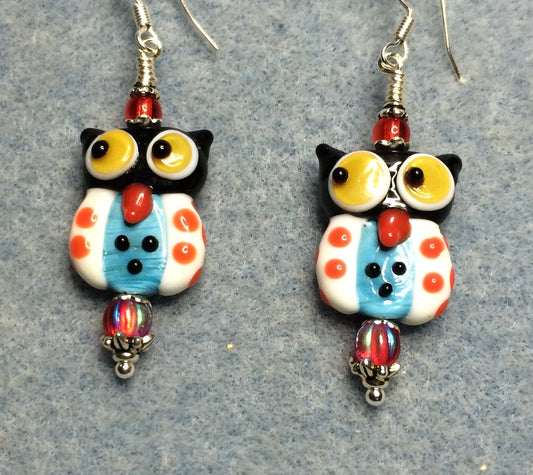 Red, white, yellow, and blue lamp work owl bead earrings adorned with red Czech glass beads.