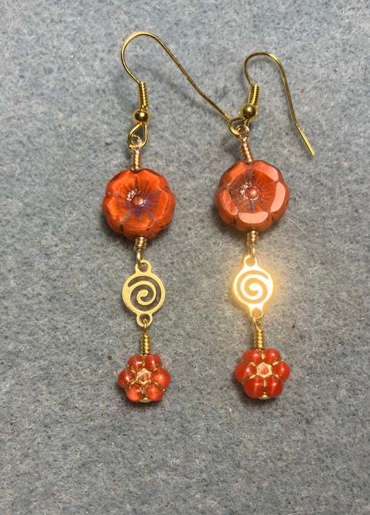 Orange Czech glass pansy bead earrings adorned with gold swirly connectors and tiny orange Czech glass daisy beads.