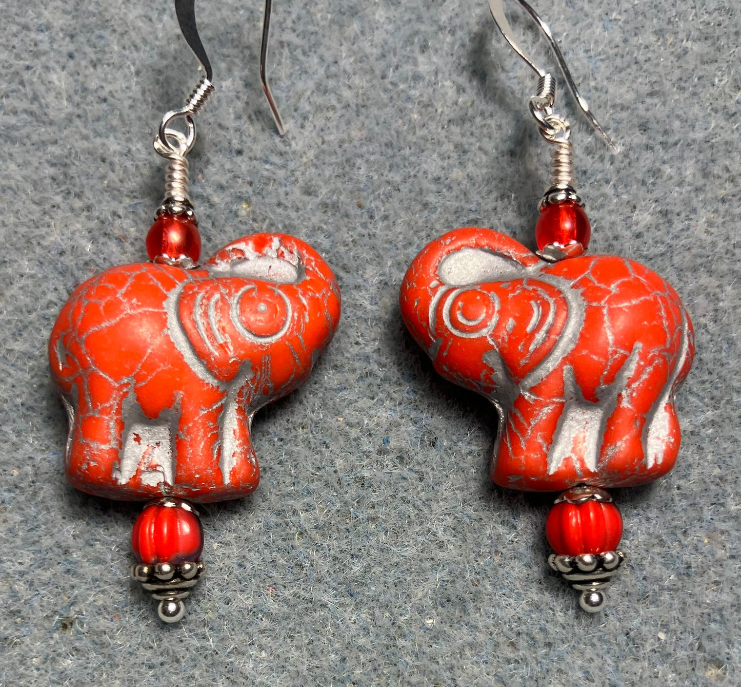 Orange red (with silver inlay) Czech glass elephant bead earrings adorned with light orange red Czech glass beads.