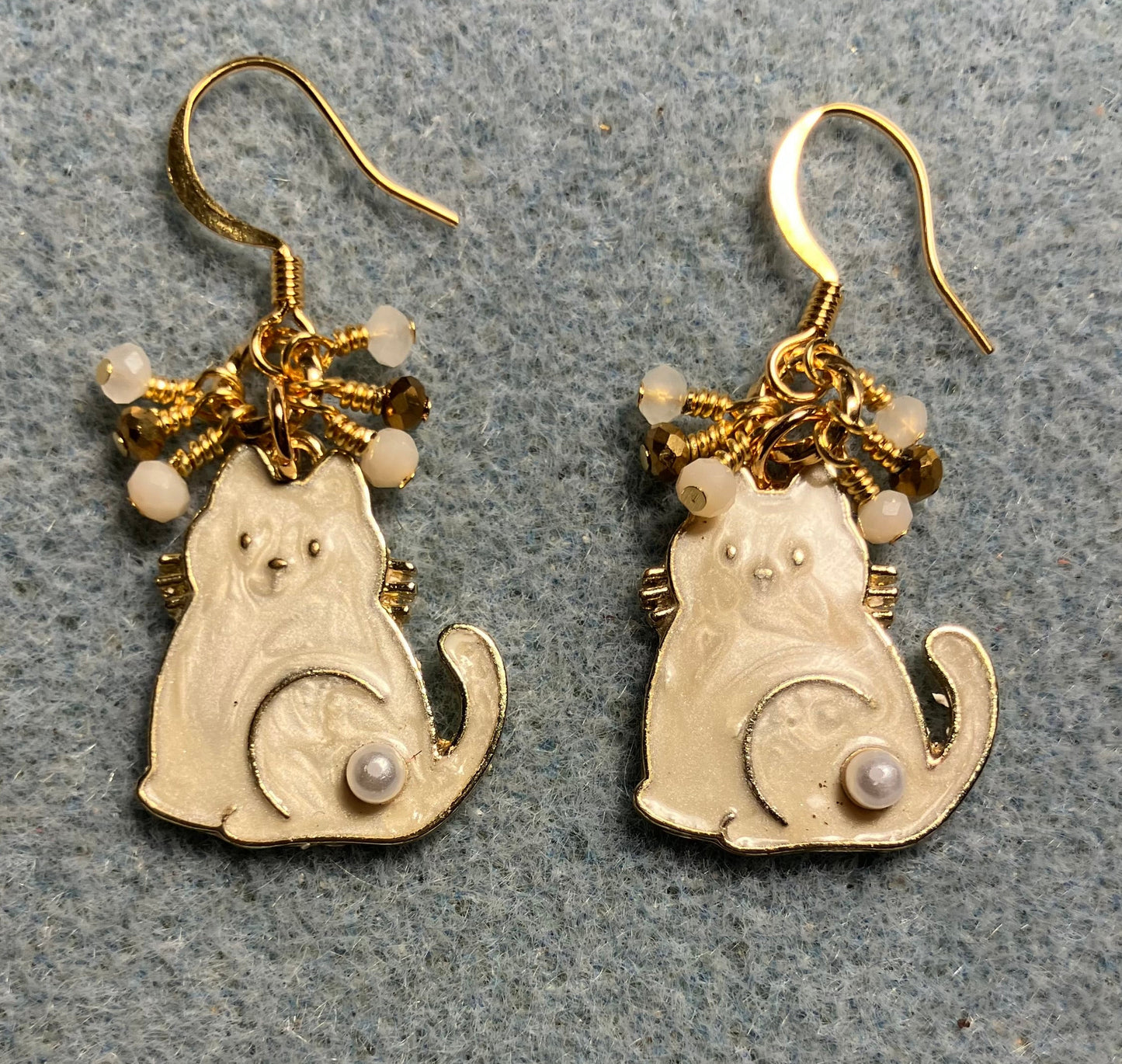 White and gold enamel and pearl cat charm earrings adorned with tiny dangling white and gold Chinese crystal beads.