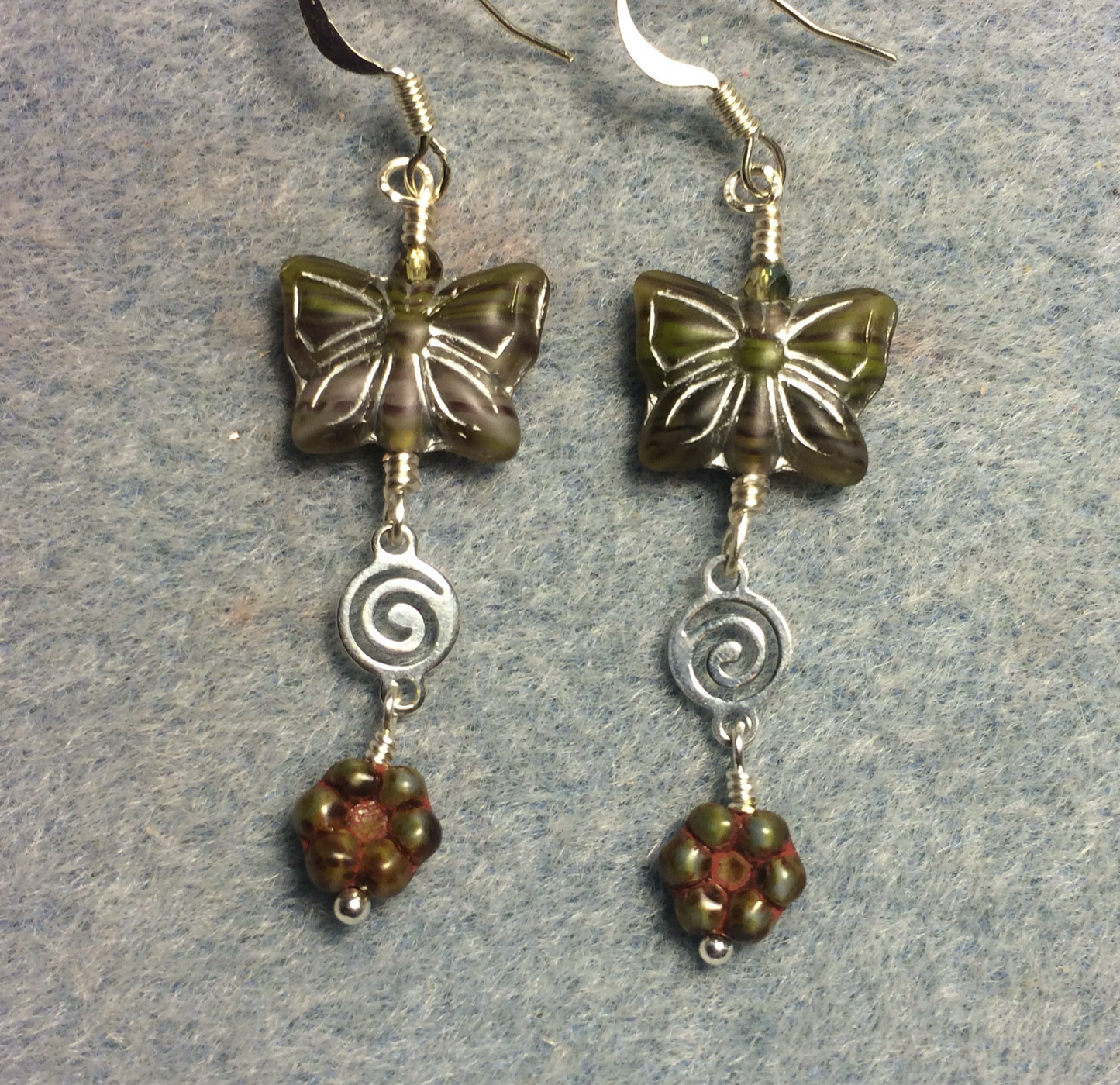 Olive green Czech glass butterfly bead earrings adorned with silver swirly connectors and olive green Czech glass daisy beads.