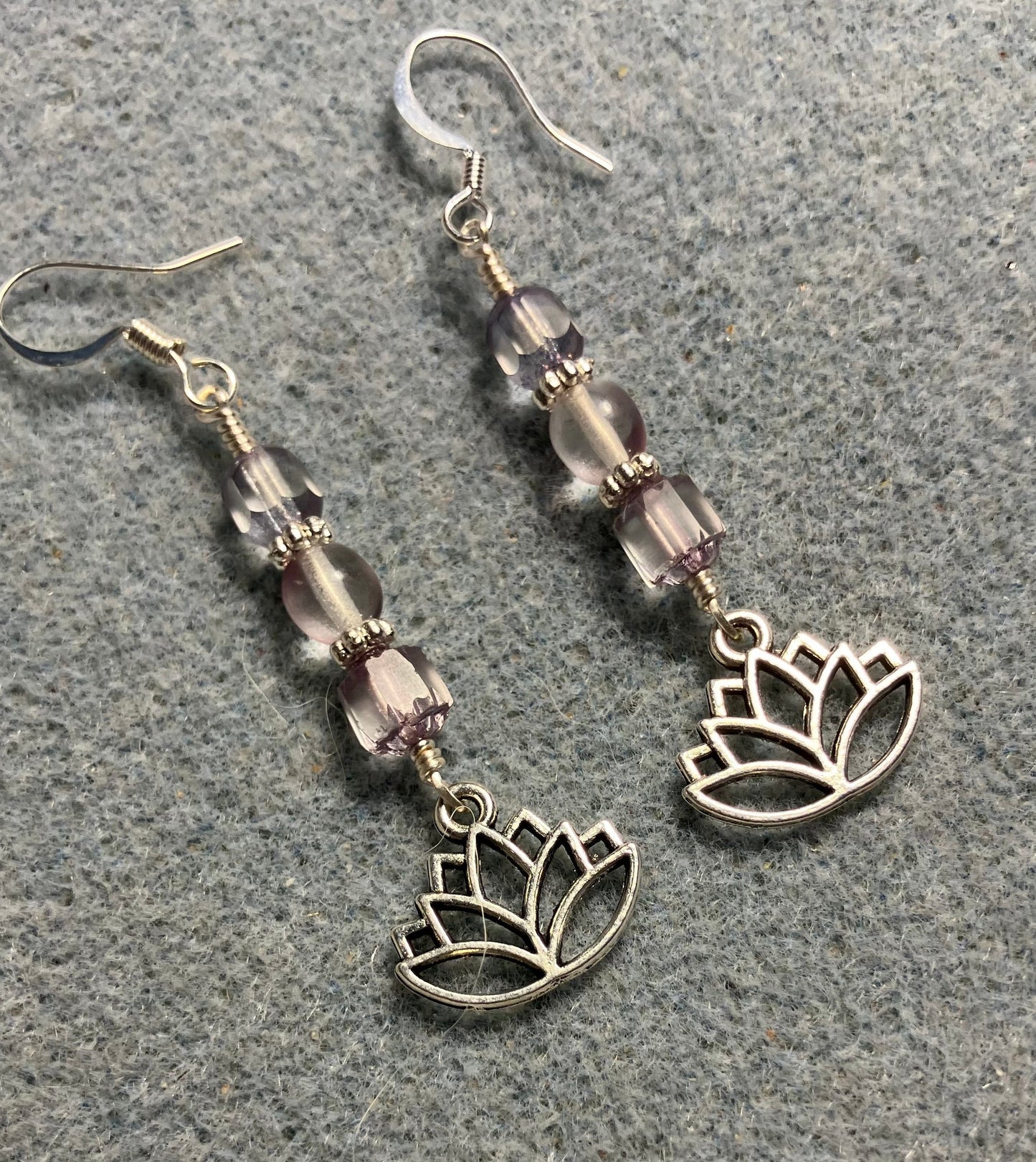 Silver lotus flower charm earrings adorned with light violet Czech glass beads.