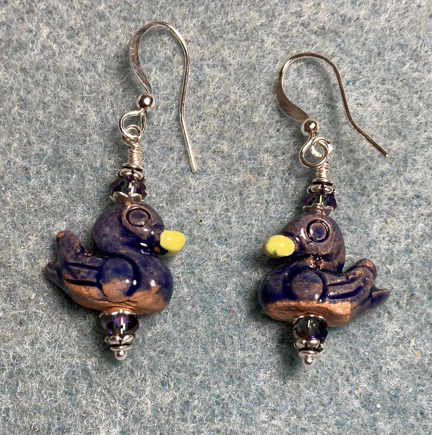 Small dark blue and yellow ceramic duck bead earrings adorned with dark blue Chinese crystal beads.