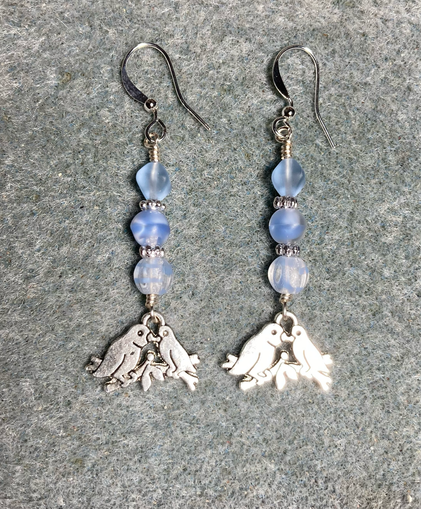 Silver pair of lovebird charm earrings adorned with light blue Czech glass beads