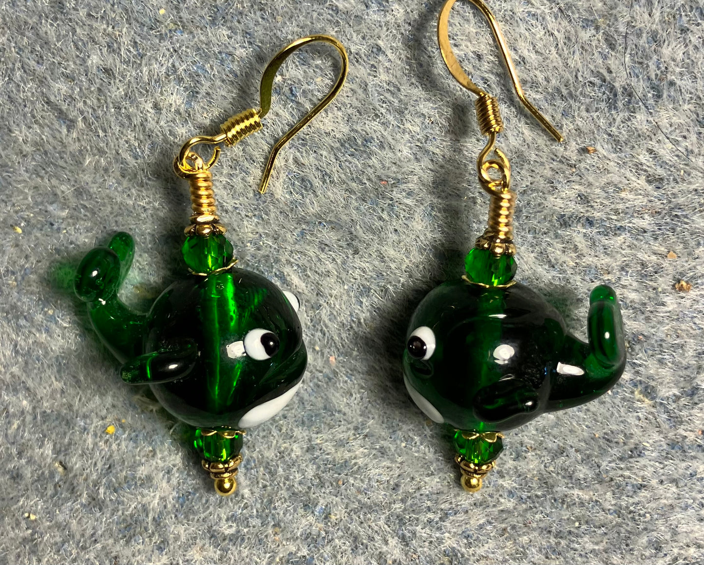 Emerald green lamp work whale bead earrings adorned with emerald green Chinese crystal beads.