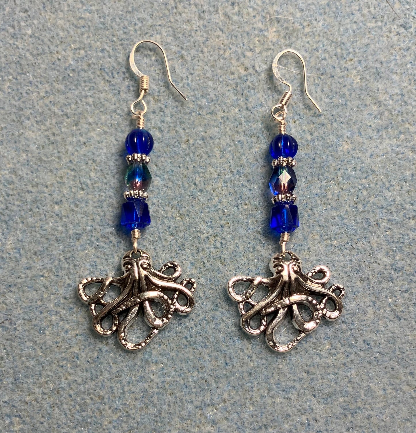Silver octopus charm earrings adorned with dark blue Czech glass beads.