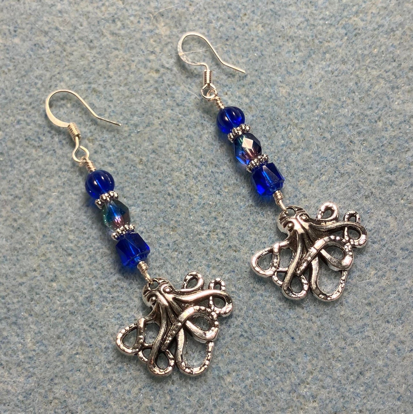 Silver octopus charm earrings adorned with dark blue Czech glass beads.