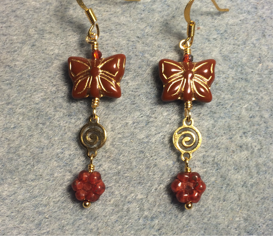 Brick red Czech glass butterfly bead earrings adorned with gold swirly connectors and brick red Czech glass daisy beads.