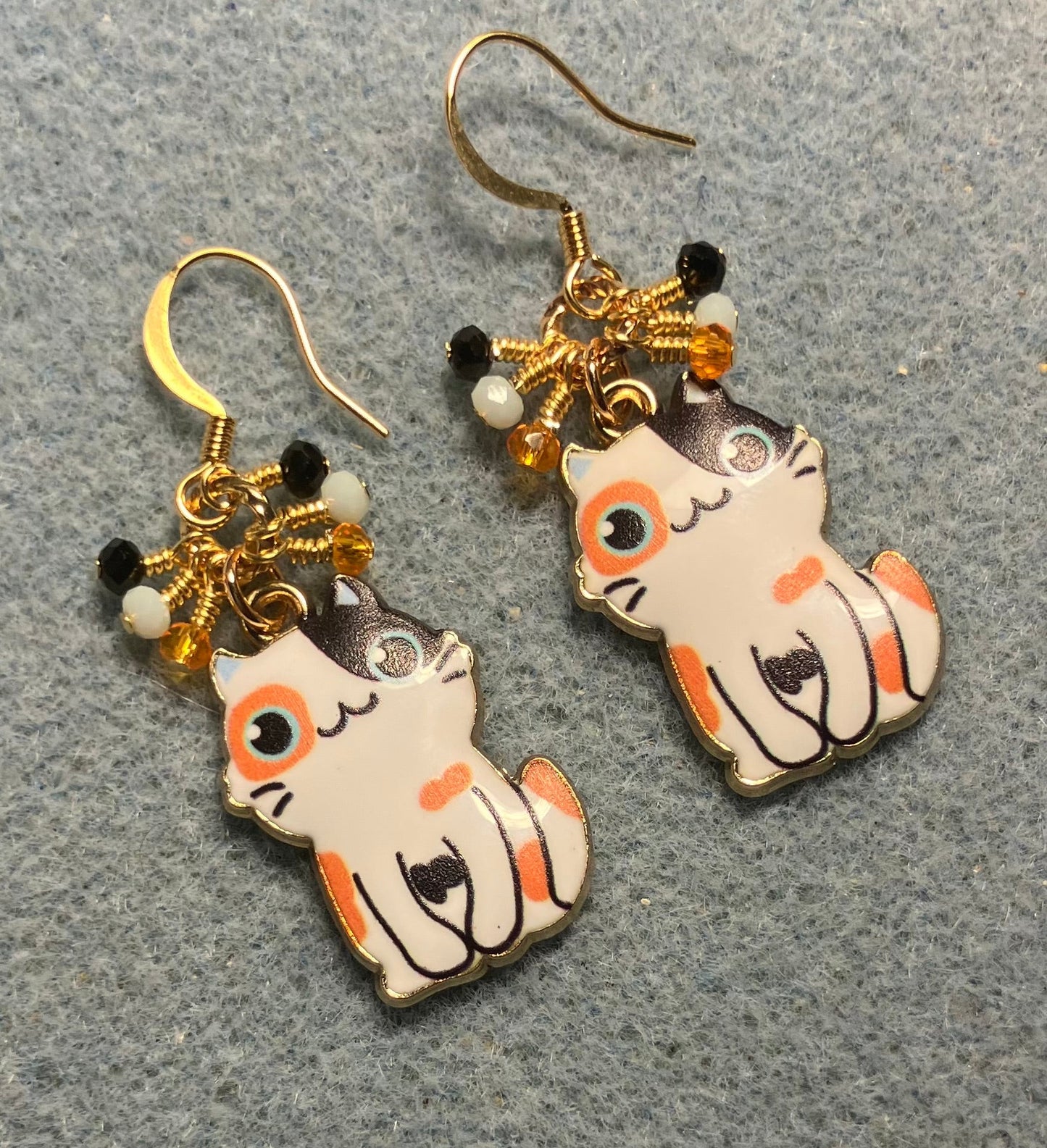Orange, white, and black enamel calico cat charm earrings adorned with tiny dangling orange, white, and black Chinese crystal beads.