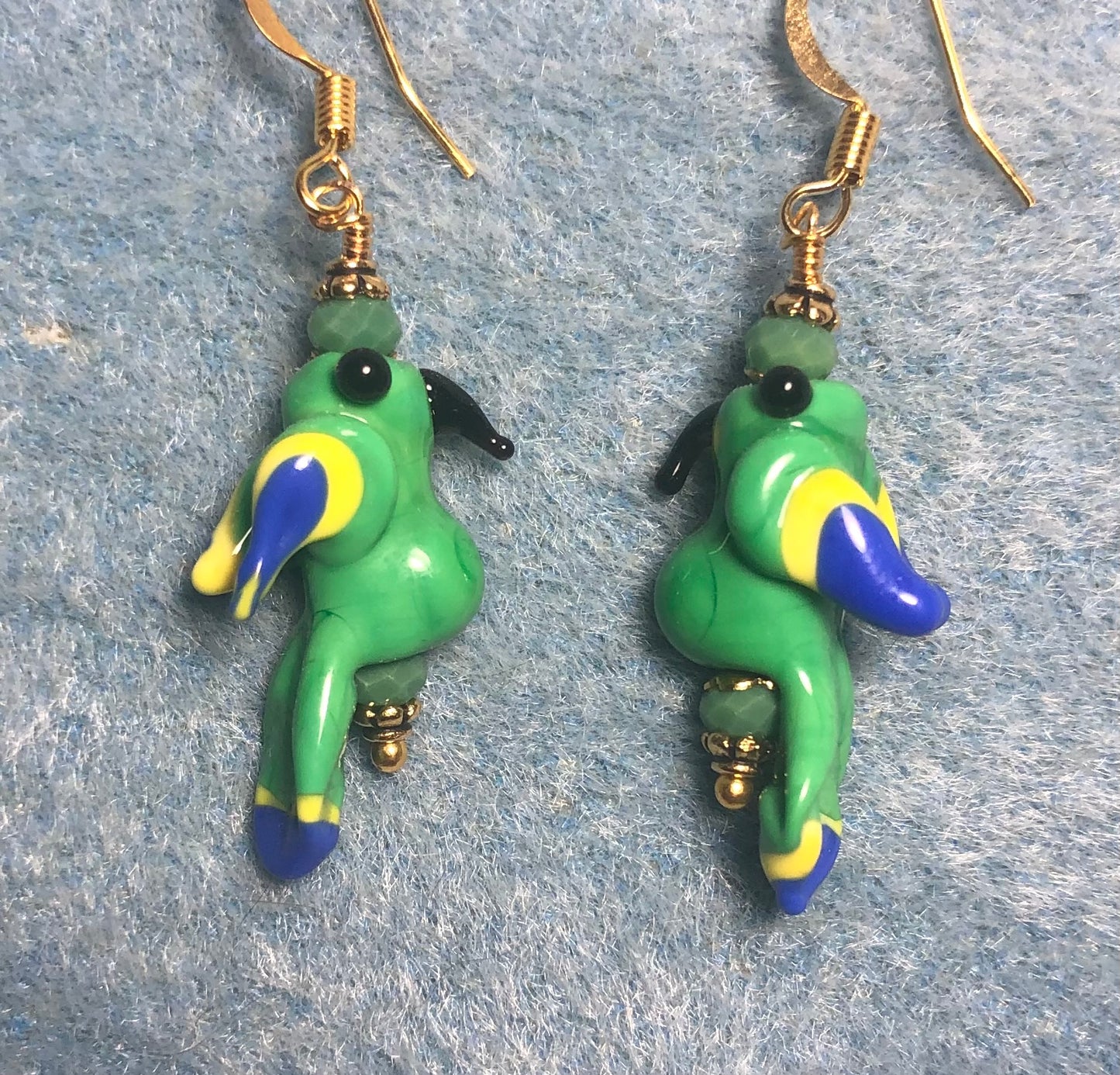 Vintage green, blue, and yellow lamp work parrot bead earrings adorned with green Chinese crystal beads.