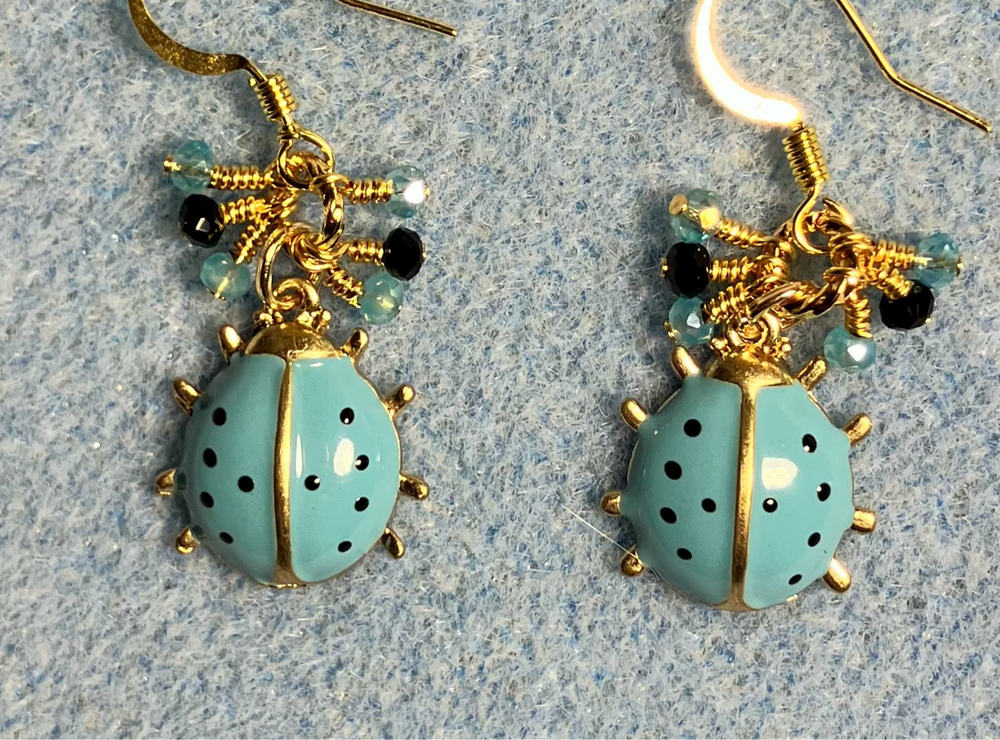 Small turquoise and black enamel ladybug charm earrings adorned with tiny dangling turquoise and black Chinese crystal beads.