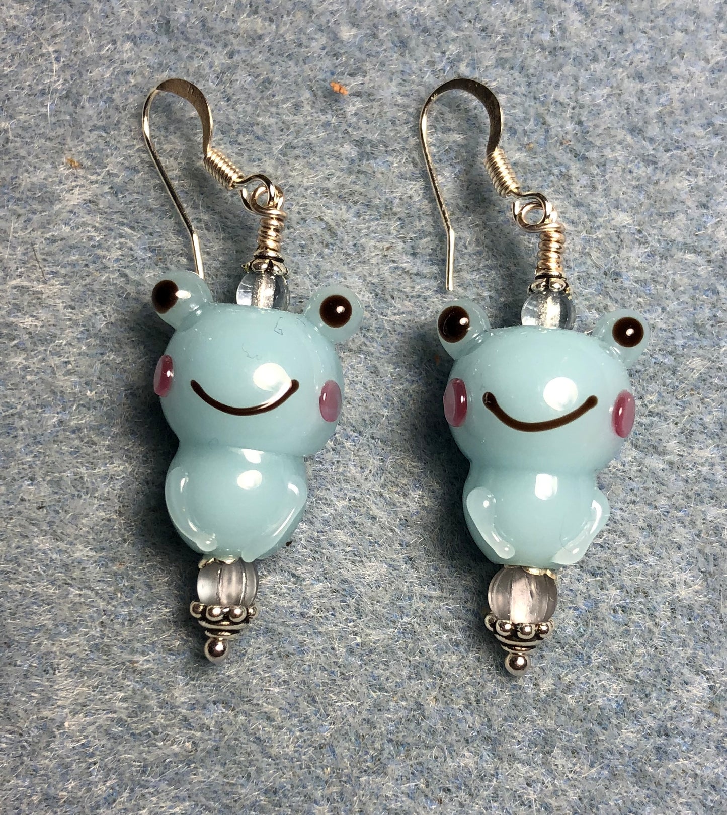 Light blue lamp work frog bead earrings adorned with light blue Czech glass beads.